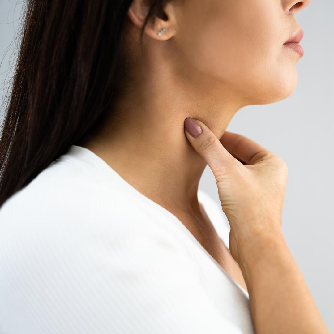 A photo of a woman from the side, massaging her neck.