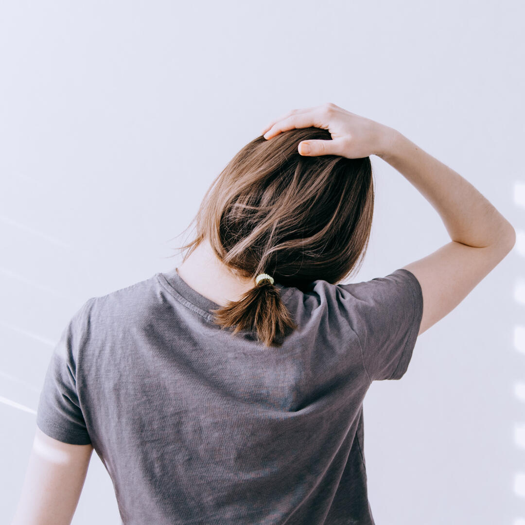 A photo of a woman from behind, stretching her neck.